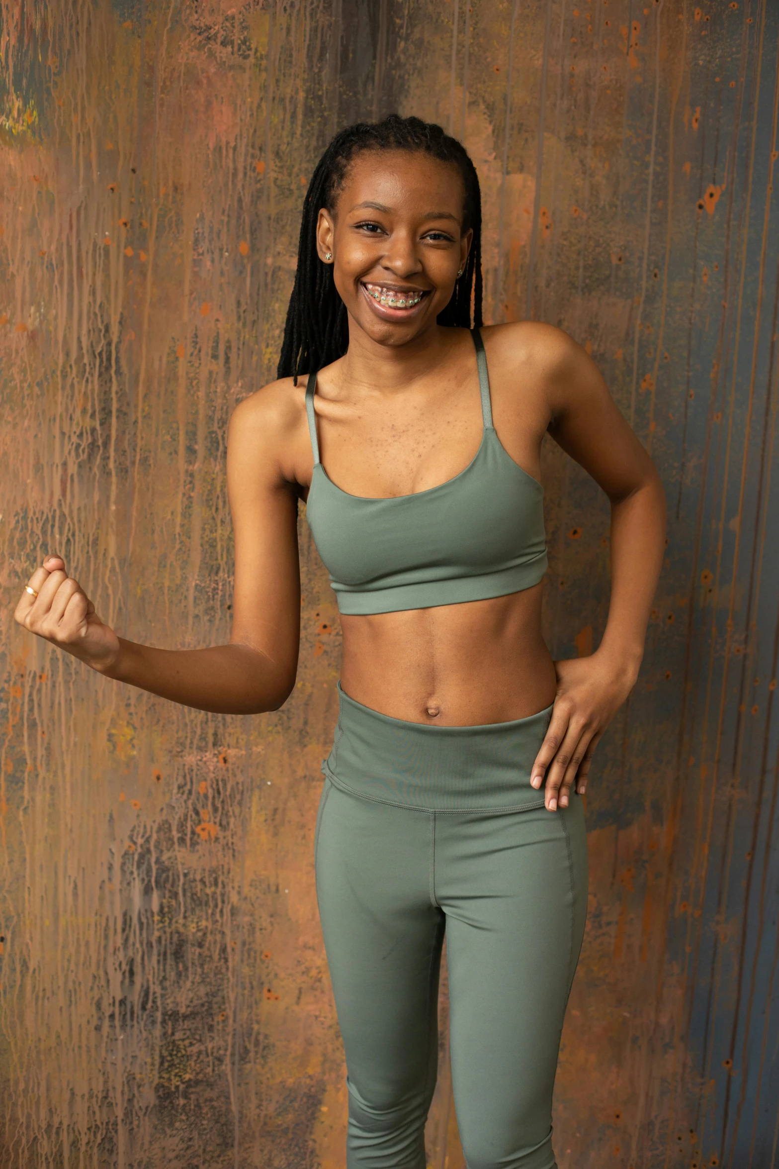 a woman in a sports bra top and leggings posing for a picture, muted green, african american young woman, detailed product image, excited