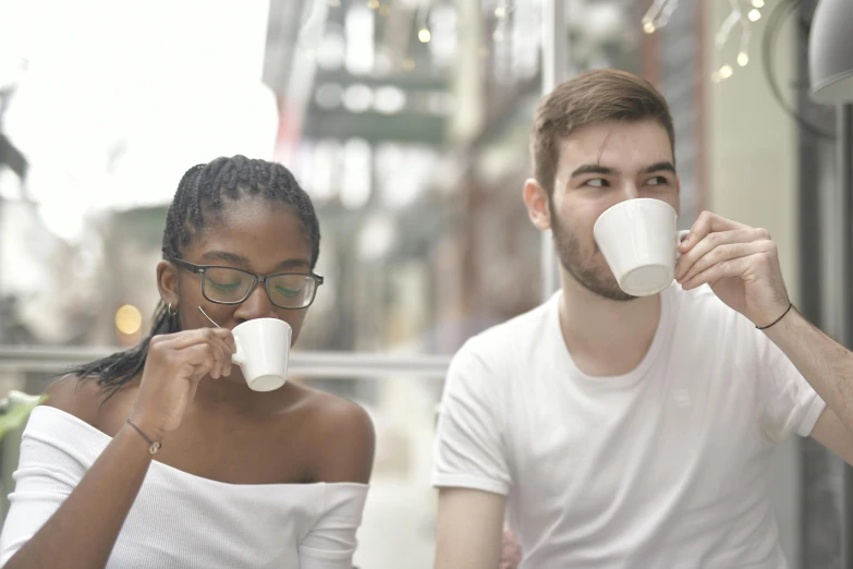 a man and a woman sitting at a table drinking coffee, pexels contest winner, white, avatar image, mixed race, handsome girl