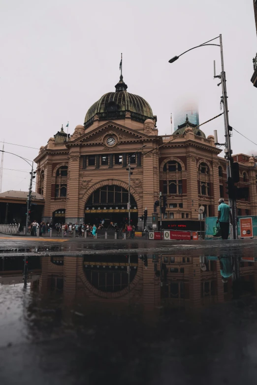 a large building with a clock on top of it, wet streets, melbourne, mirrors everywhere, train station