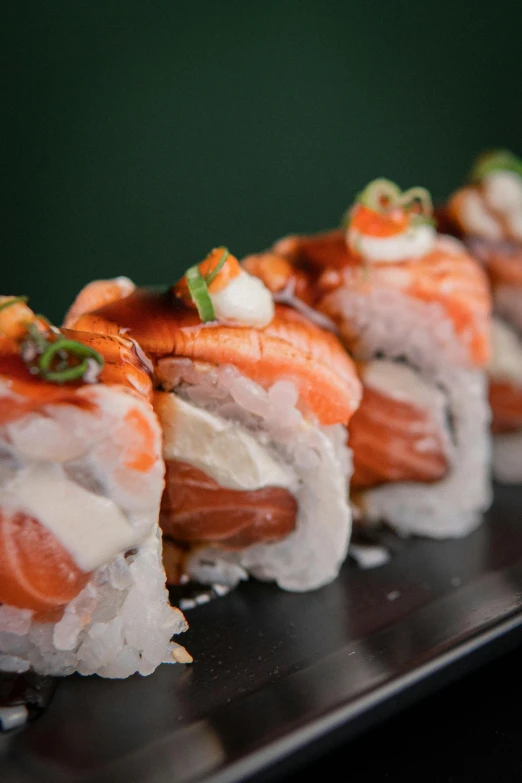 a row of sushi sitting on top of a black plate, daily specials, over the shoulder, great wave, striking pose