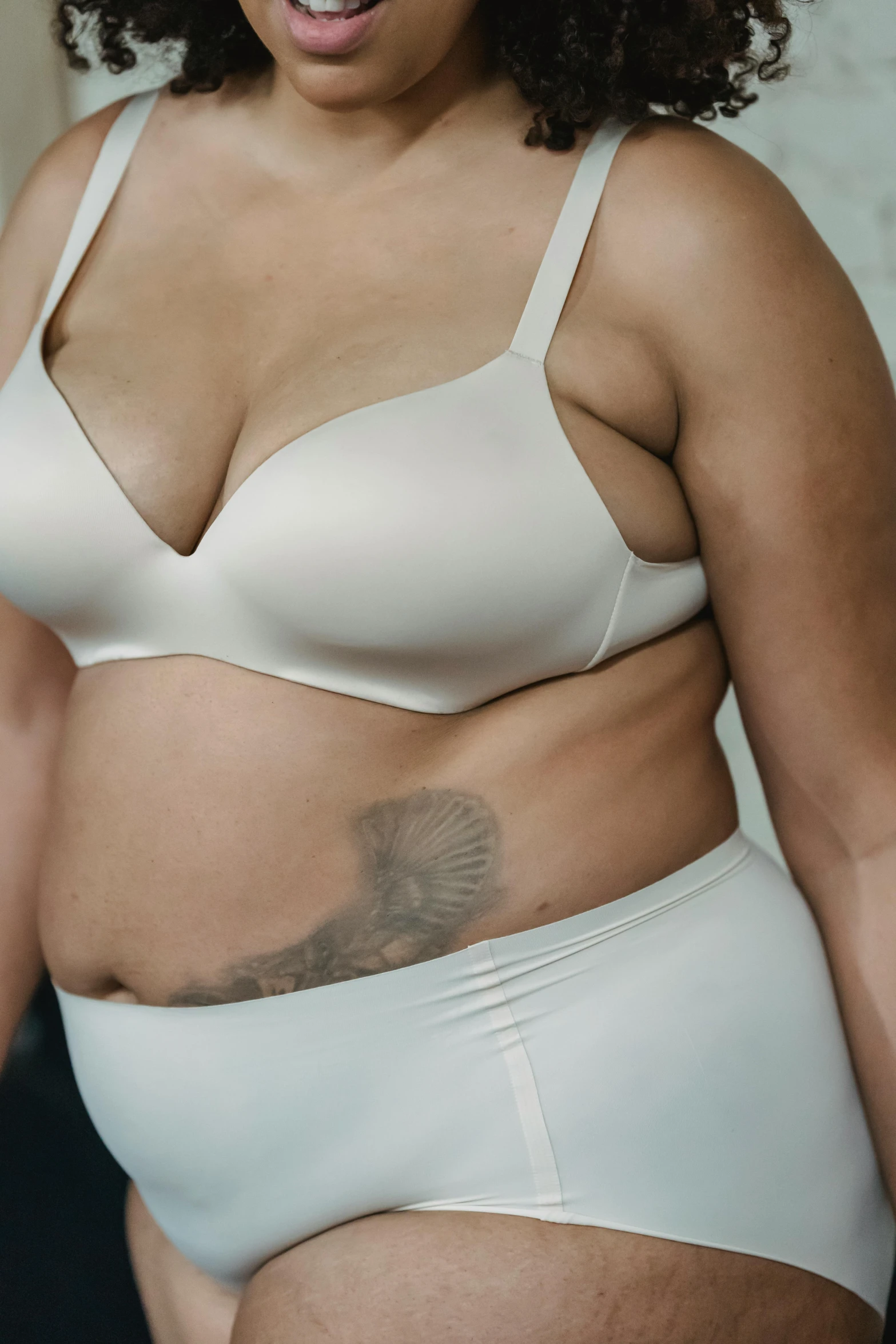 a woman in a white underwear posing for a picture, a tattoo, bloated, ad image, wearing bra, uncropped