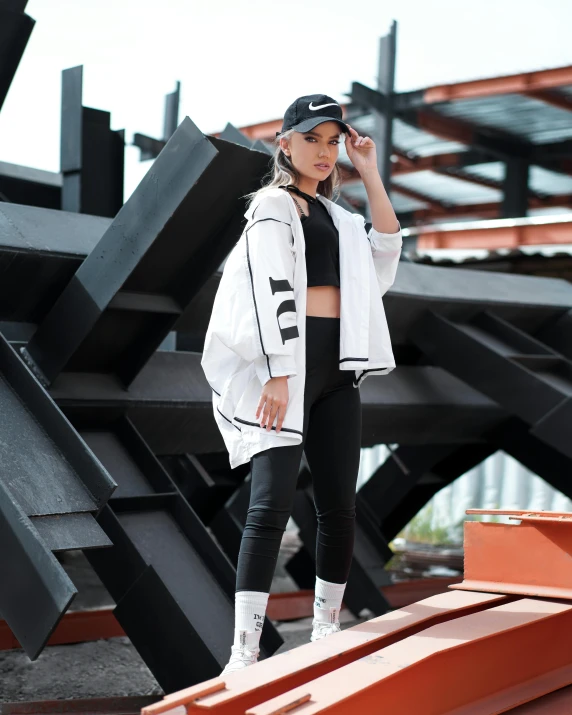 a woman wearing a white jacket and black pants, unsplash, she is wearing streetwear, in an arena pit, official store photo, asher duran