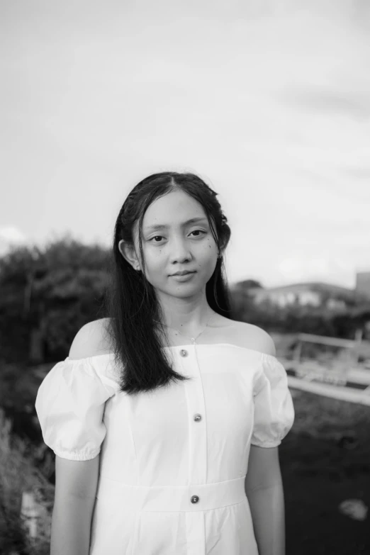 a woman standing in front of a body of water, a black and white photo, inspired by Tang Yifen, head and shoulders portrait, young woman with long dark hair, lin hsiang, portrait of a young teenage girl