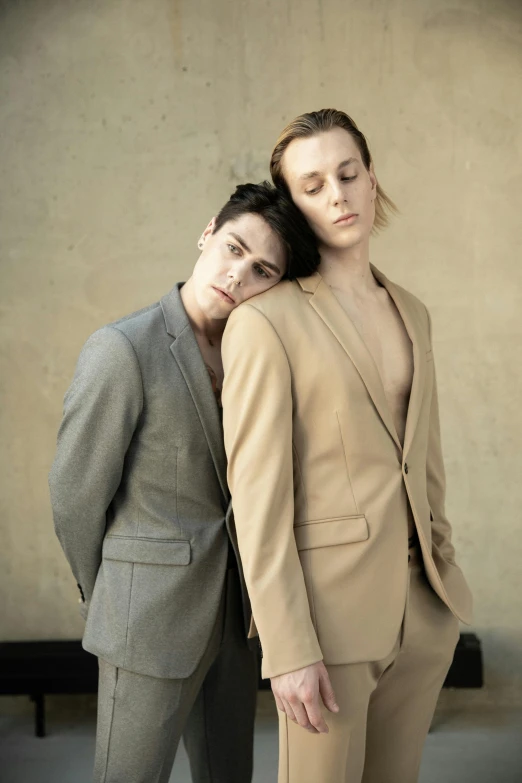 a couple of people standing next to each other, by Matija Jama, bauhaus, wearing a worn out brown suit, lesbian embrace, joel fletcher, lachlan bailey