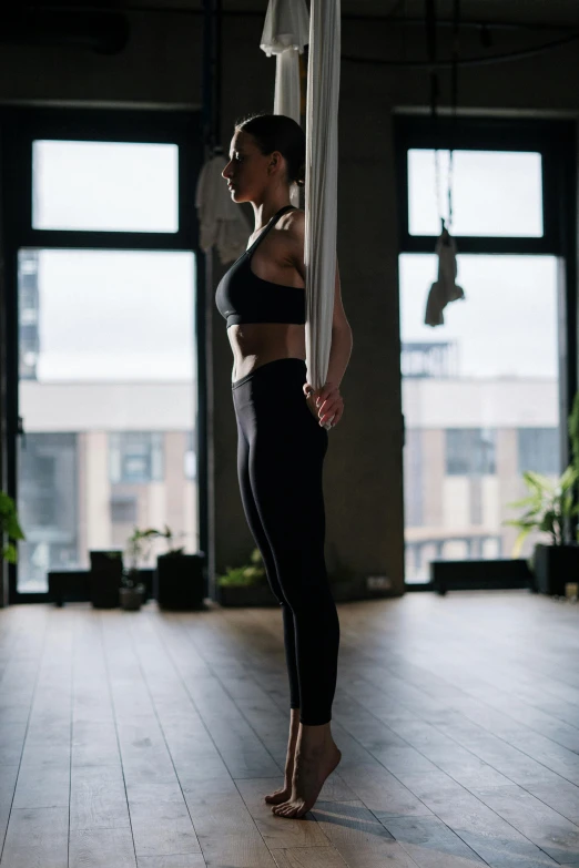 a woman standing on a pole in a room, pexels contest winner, arabesque, wearing fitness gear, ready to fly, square, neo kyiv