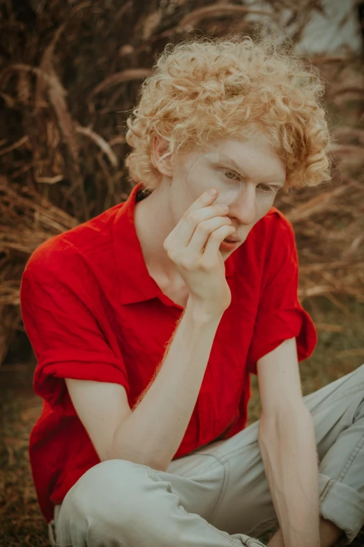 a man in a red shirt sitting on the ground, unsplash, renaissance, pale skin curly blond hair, hr ginger, tall and lanky skinny, ((red)) baggy eyes