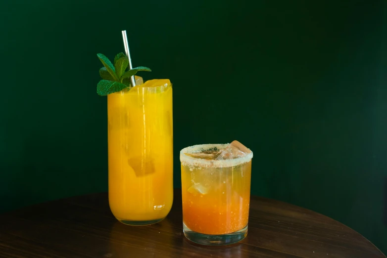 a couple of drinks sitting on top of a wooden table, by Carey Morris, unsplash, yellow and greens, orange, closed limbo room, 15081959 21121991 01012000 4k