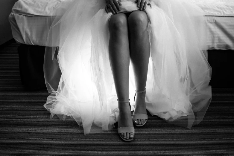 a woman in a wedding dress sitting on a bed, a black and white photo, by Greg Spalenka, pexels, sandals, 🤬 🤮 💕 🎀, wearing a tutu, sheer