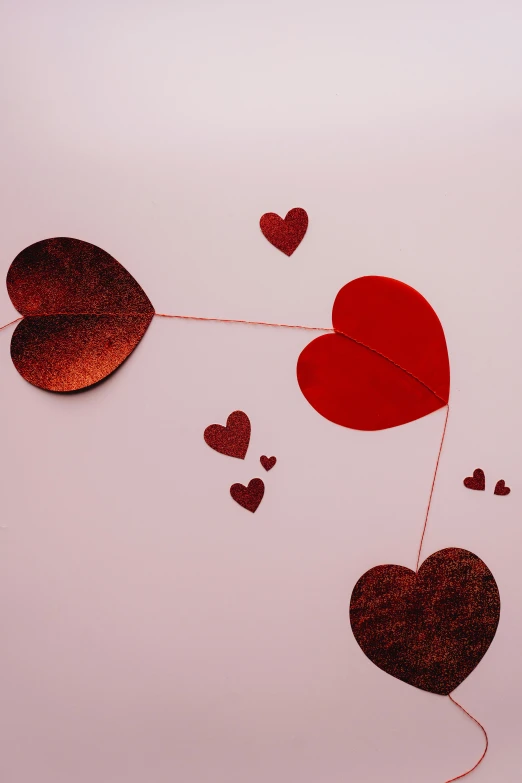 a couple of red hearts hanging from a string, an album cover, trending on pexels, romanticism, demur, laser cut, glitter, chocolate