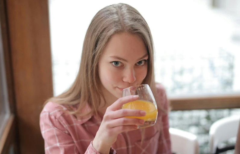 a woman drinking a glass of orange juice, by Adam Marczyński, pexels, renaissance, teenager girl, full face, gif, is ((drinking a cup of tea))