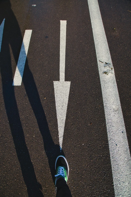 a shadow of a person walking across a street, by Niko Henrichon, unsplash, metallic arrows, some of the blacktop is showing, two legs, 15081959 21121991 01012000 4k