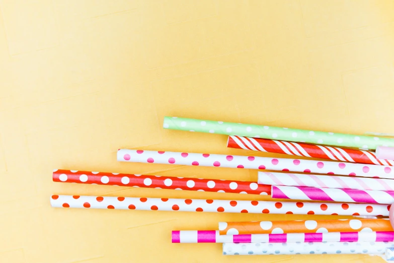 a bunch of paper straws sitting on top of a table, an album cover, pexels, pop art, polkadots, plain background, square, summer color pattern