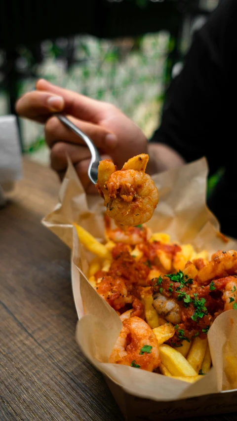 a person sitting at a table with a basket of food, pexels, photorealism, shrimp, chips, using fork, battered