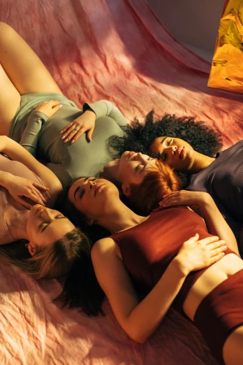 a group of women laying on top of a bed, inspired by Nan Goldin, trending on pexels, renaissance, multicoloured, dreamy soft, top angle, idyll