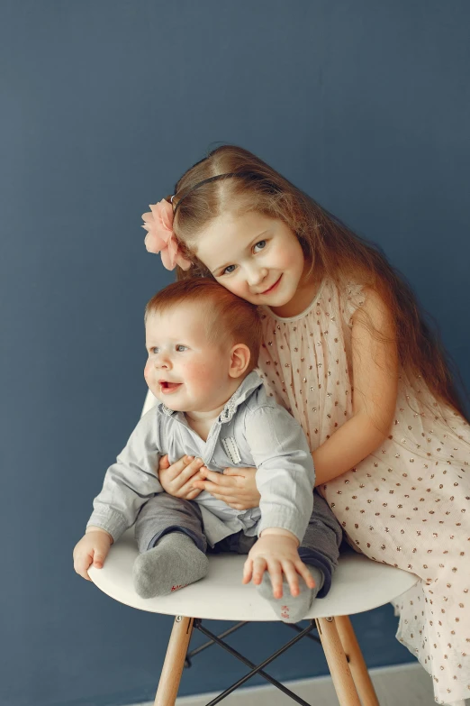 a couple of kids sitting on top of a chair, grey backdrop, slide show, portrait image, small