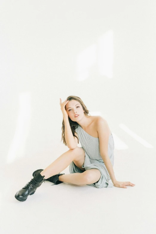 a woman sitting on the ground with her legs crossed, unsplash, light and space, transparent gray dress, portrait sophie mudd, doing a sassy pose, set against a white background