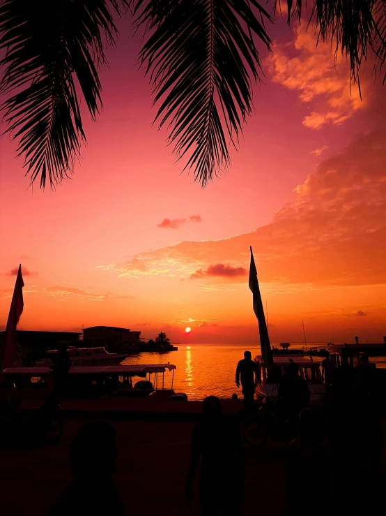 a couple of umbrellas sitting on top of a sandy beach, orange and red sky, maldives in background, profile image, ((sunset))