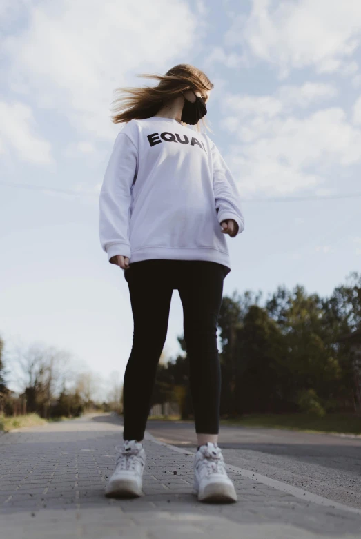 a woman riding a skateboard down the middle of a road, an album cover, by Dulah Marie Evans, trending on unsplash, wearing sweatshirt, profile image, white leggings, squad