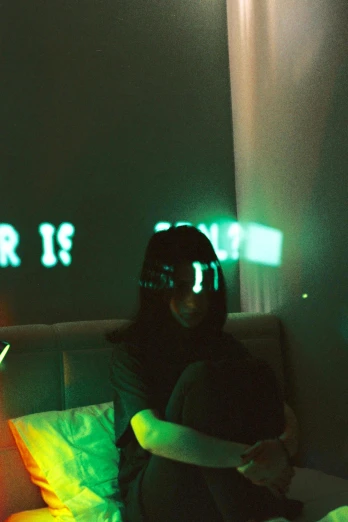 a woman sitting on a bed in a dark room, a hologram, inspired by Elsa Bleda, unsplash, holography, glowing street signs, vivid green lasers, ulzzang, vhs filter