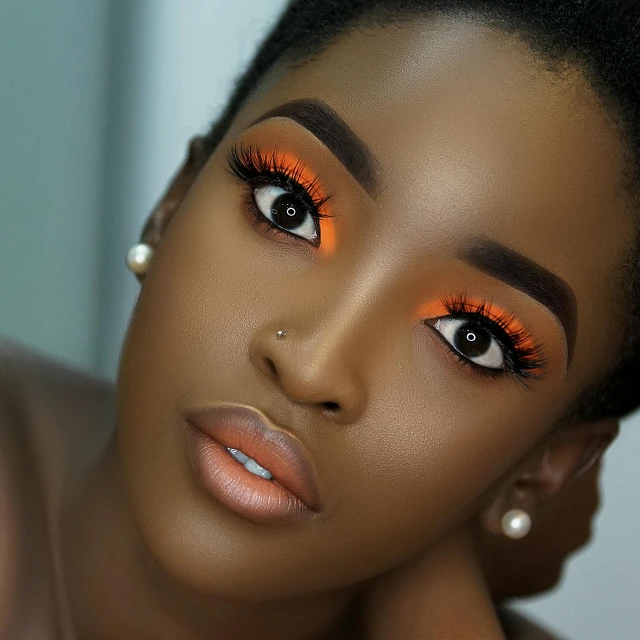 a close up of a woman with orange makeup, trending on pexels, dark complexion, lashes, joyful look, gradient orange