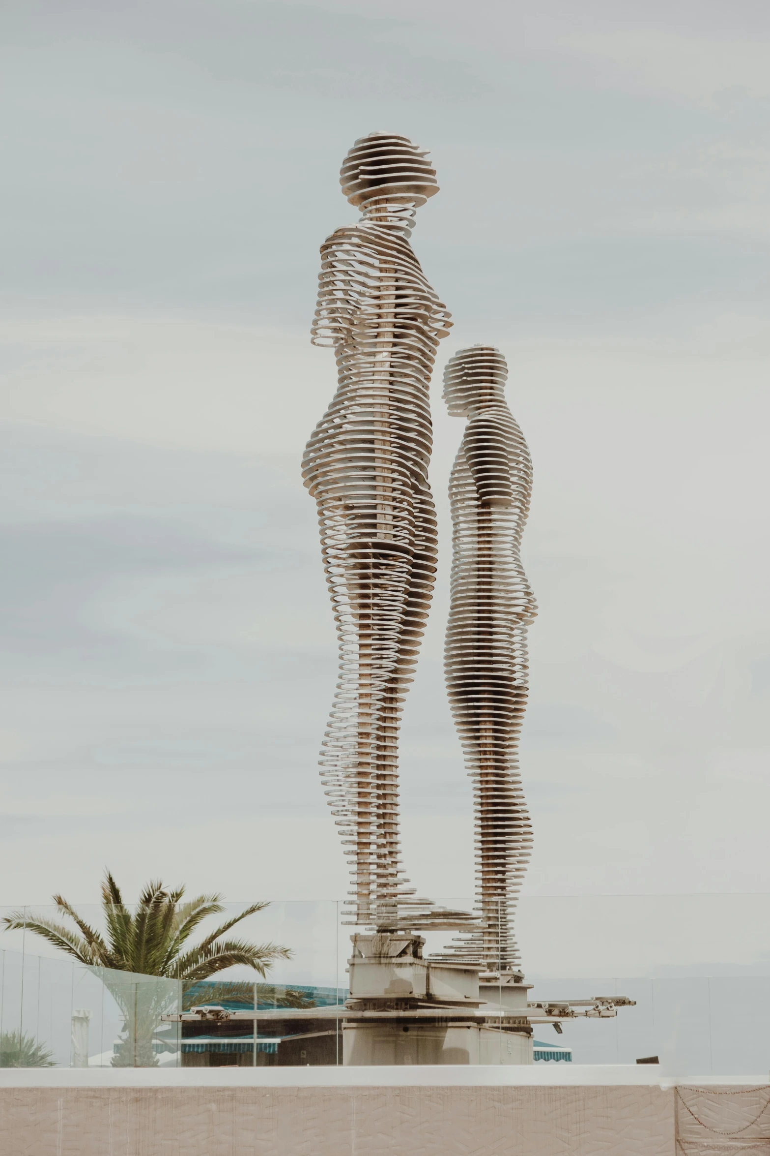 a couple of statues sitting on top of a cement wall, a surrealist sculpture, by Gavin Hamilton, unsplash, marbella, made of steel, parametric structure, rendering of beauty pageant