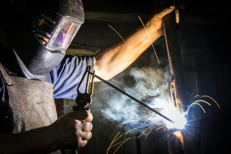 a man in a welding mask working on a piece of metal, by Tom Bonson, pexels contest winner, arbeitsrat für kunst, wielding a crowbar, australian, stick poke, night time