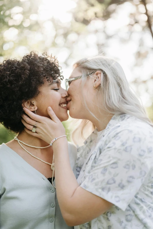 a couple of women standing next to each other, trending on unsplash, kissing together, diverse ages, silver curly hair, plus-sized