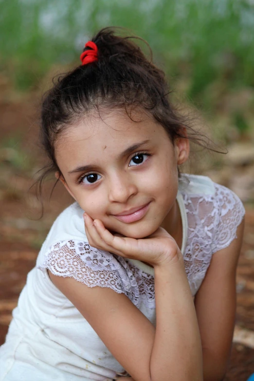 a little girl laying on the ground with a frisbee, by Lilia Alvarado, pixabay contest winner, arab ameera al-taweel, lovingly looking at camera, with brown skin, hand on cheek