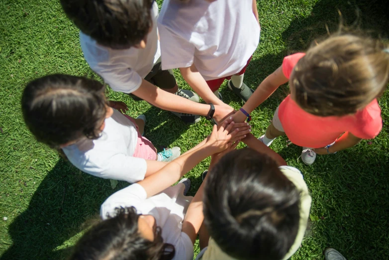 a group of children standing on top of a lush green field, holding each other hands, tournament, 15081959 21121991 01012000 4k, top - down photograph