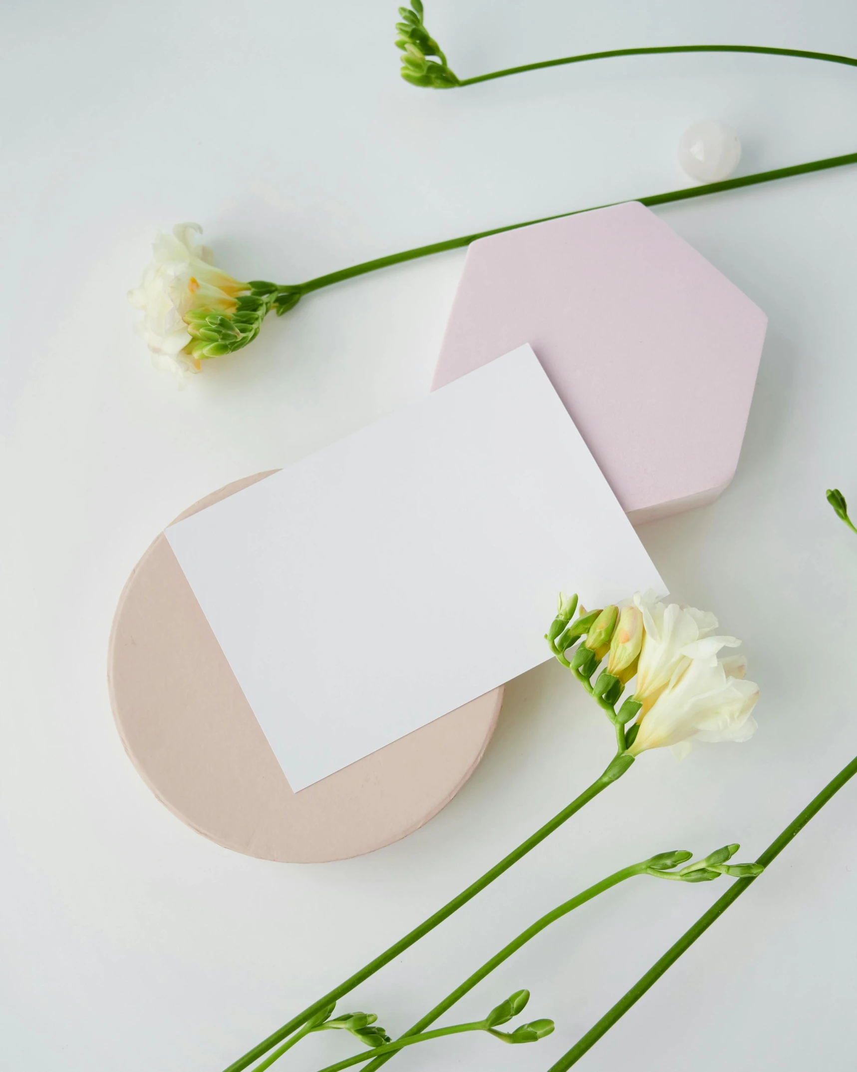 flowers and a blank card on a white surface, inspired by Eden Box, unsplash, hexagonal shaped, pastel pink concrete, pair of keycards on table, made of all white ceramic tiles