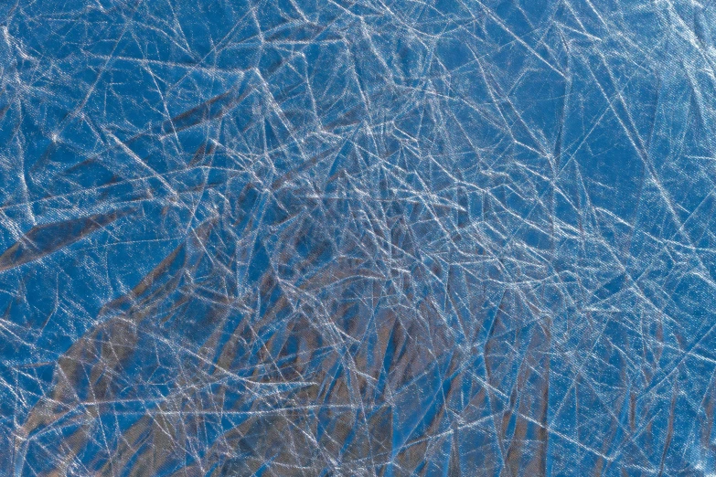 a man riding skis down a snow covered slope, a microscopic photo, inspired by Vija Celmins, pexels, abstract expressionism, blue-fabric, webs, metallic surface, frosted glass