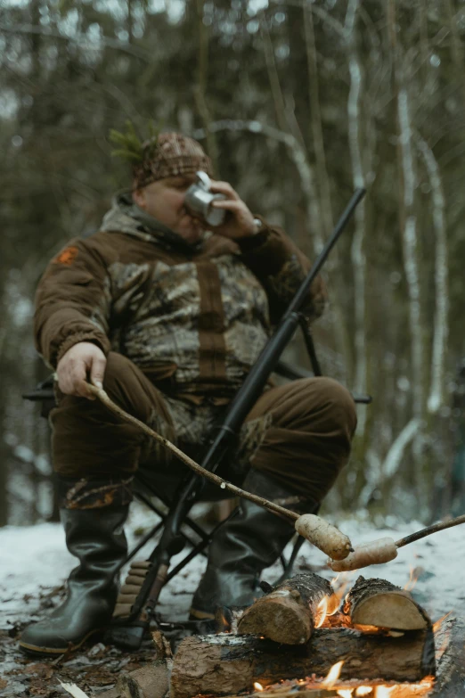 a man sitting in a chair next to a fire, hunters gear, eating, **cinematic, fishing pole