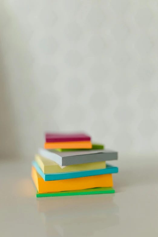 a stack of books sitting on top of a table, ink on post it note, toy photography, multicolor, square