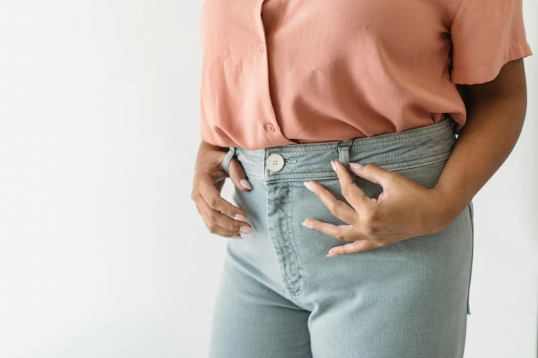 a woman standing with her hands in her pockets, trending on pexels, figuration libre, grey metal body, wearing a light blue shirt, heavy gesture style closeup, big stomach