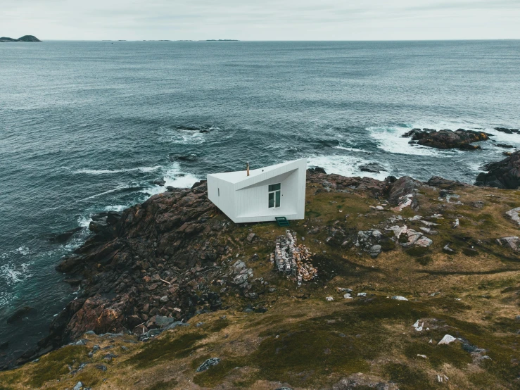 a white house sitting on top of a hill next to the ocean, by Jessie Algie, pexels contest winner, conceptual art, tiny house, views to the ocean, victoria siemer, wide aerial shot