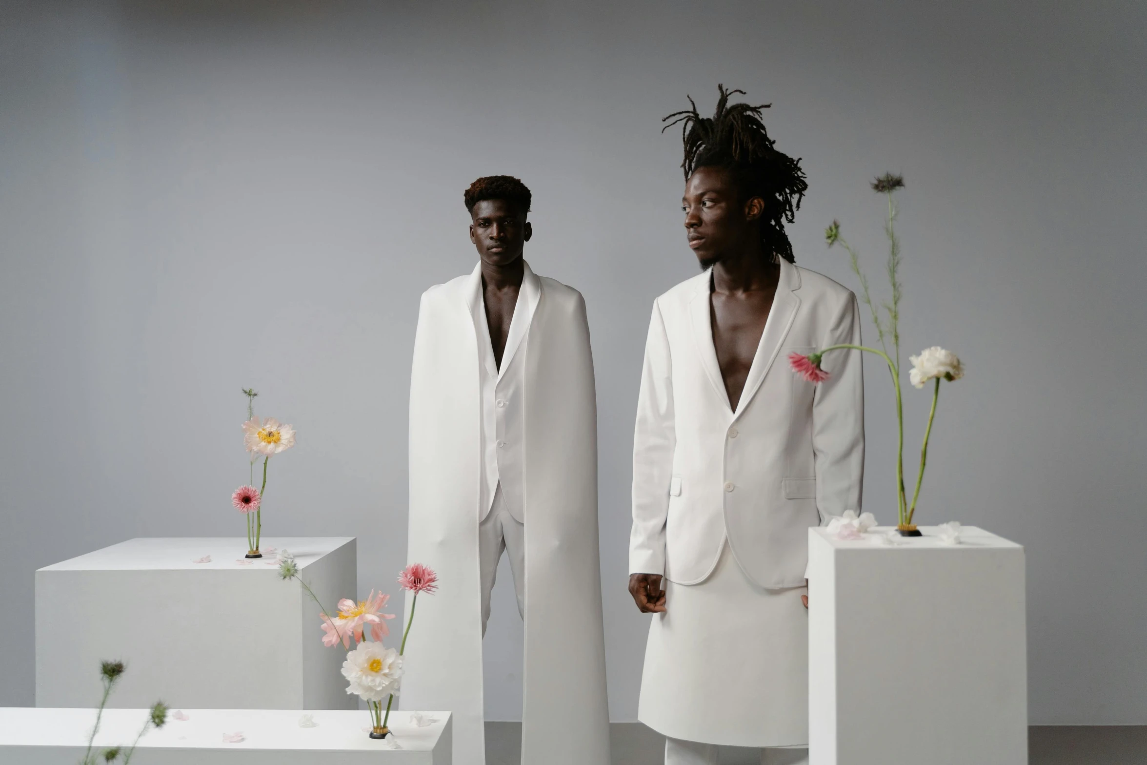 a couple of men standing next to each other, inspired by Barthélemy Menn, wearing futuristic white suit, tall flowers, adut akech, 165 cm tall