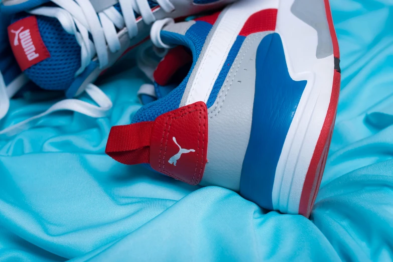 a close up of a pair of shoes on a bed, by Matija Jama, figuration libre, brand colours are red and blue, puma, multilayer, detailed zoom photo