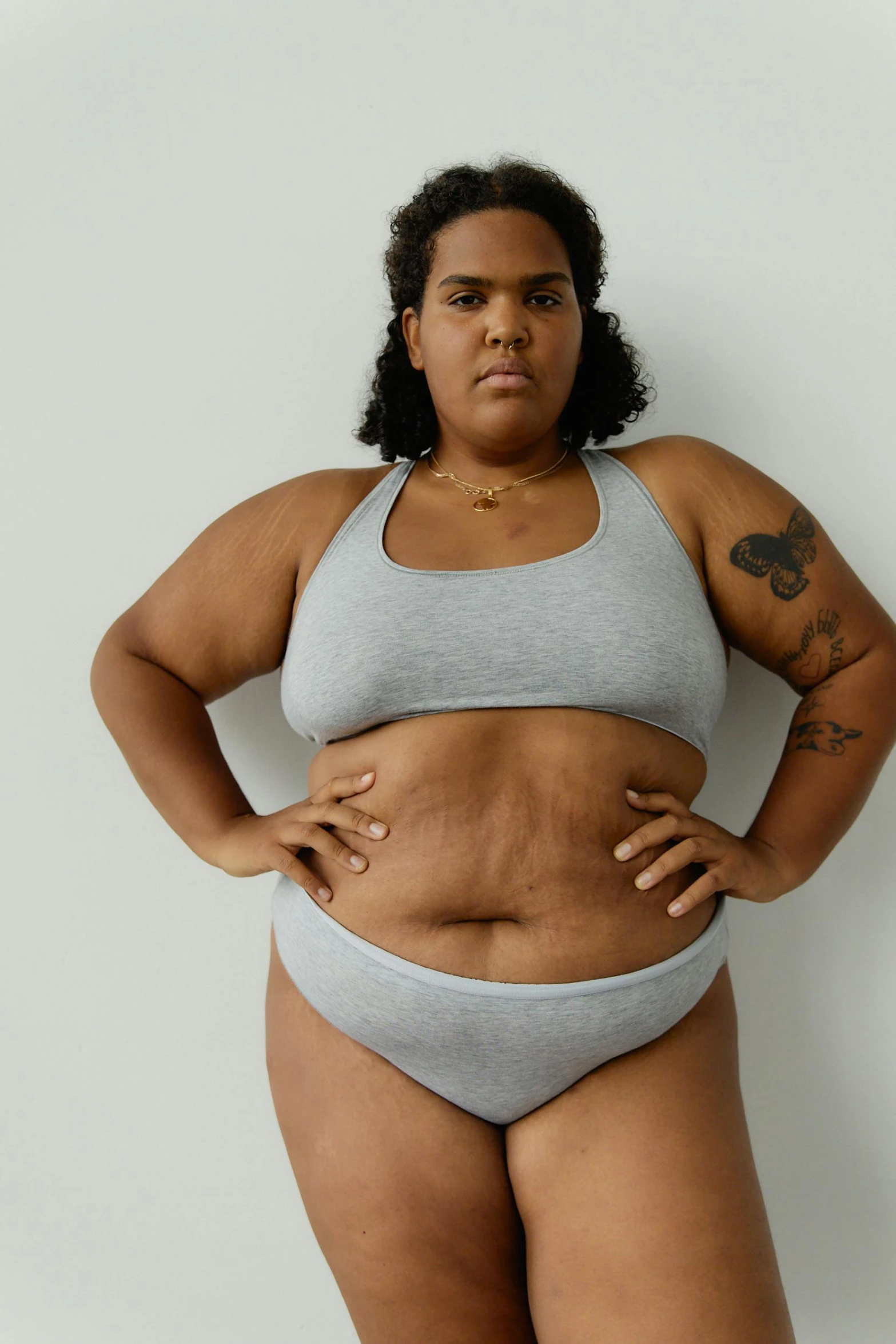 a woman in a gray bikini posing for a picture, an album cover, inspired by Louisa Matthíasdóttir, trending on pexels, overweight, mixed-race woman, crop top, non-binary