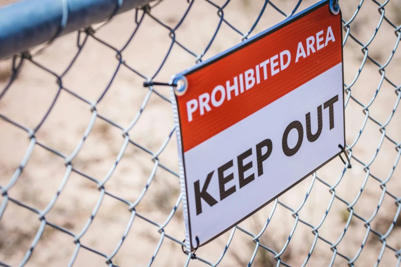 a keep out sign on a chain link fence, by Matt Cavotta, shutterstock, geology, half image, a labeled, with no problems