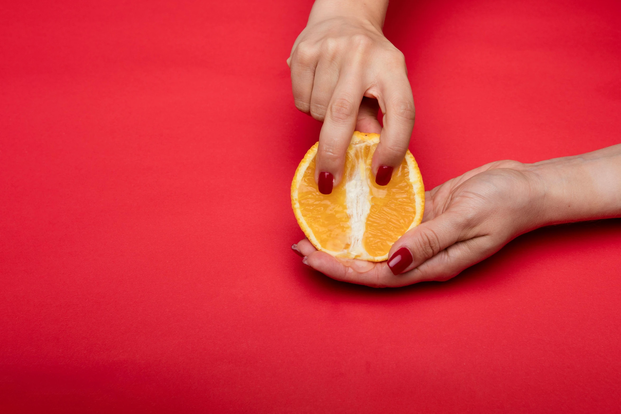 a close up of a person holding an orange, magic realism, on a red background, food stylist, chopping hands, press shot