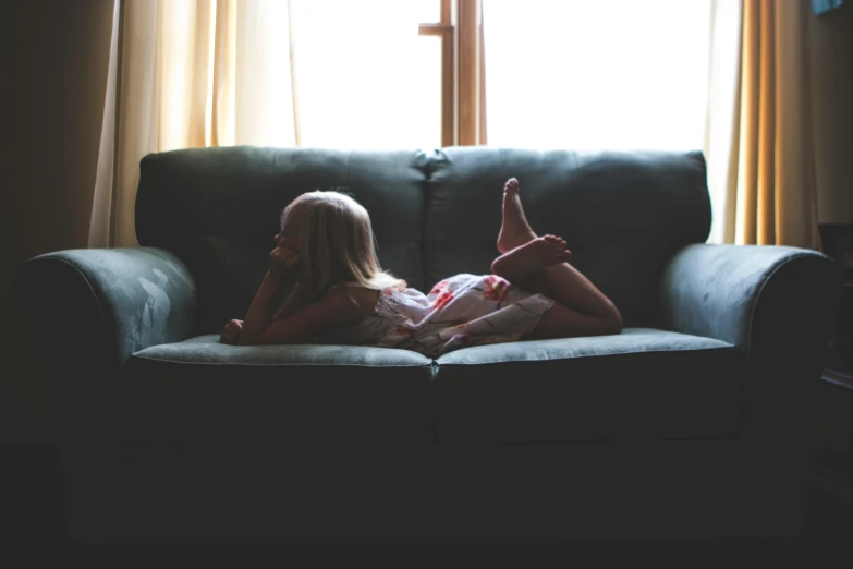 a little girl laying on a couch reading a book, inspired by Elsa Bleda, pexels contest winner, facing away, 15081959 21121991 01012000 4k, summer light, old couch