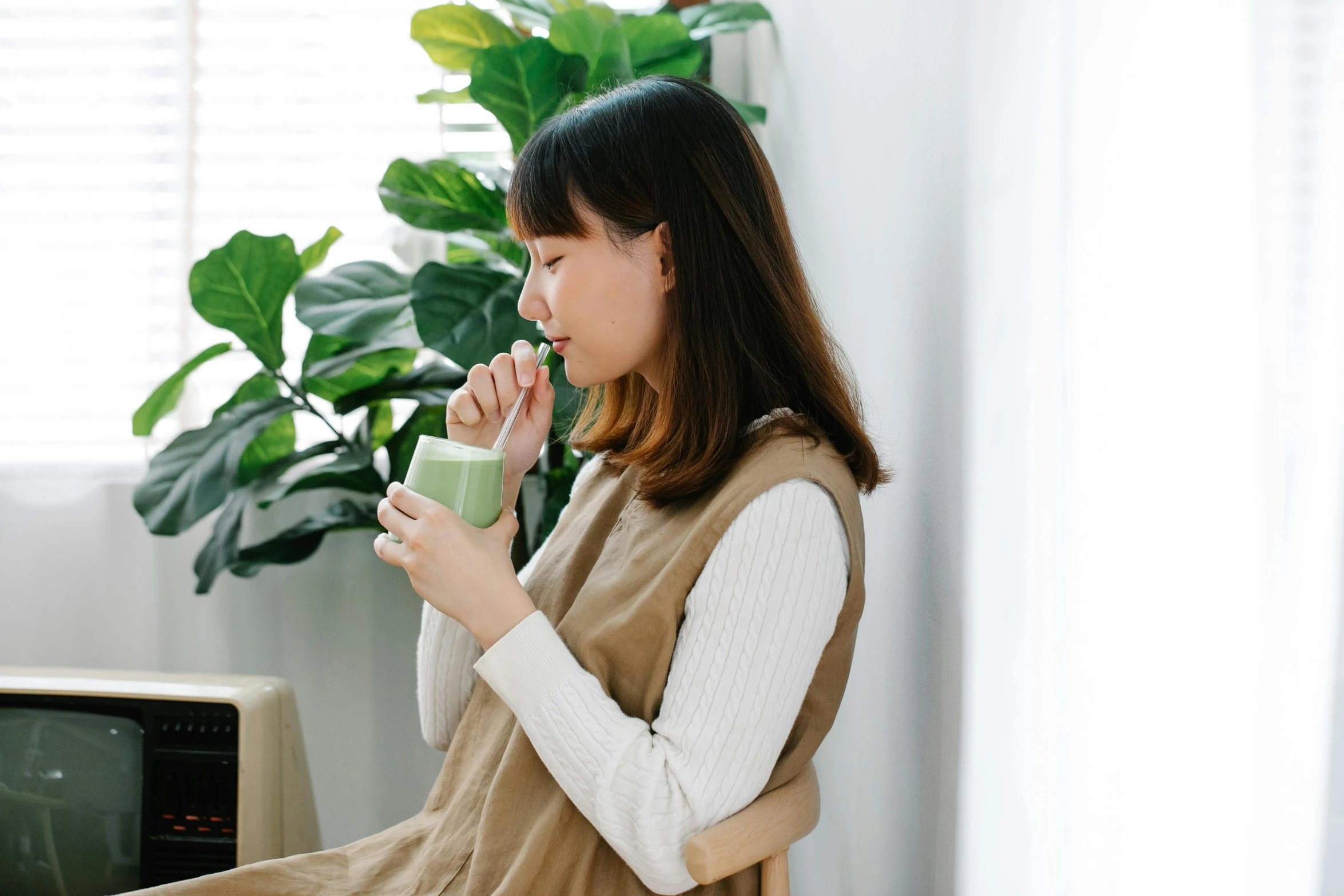 a woman sitting on a chair drinking a green drink, inspired by Ruth Jên, trending on pexels, japanese collection product, maternity feeling, profile image, having a snack