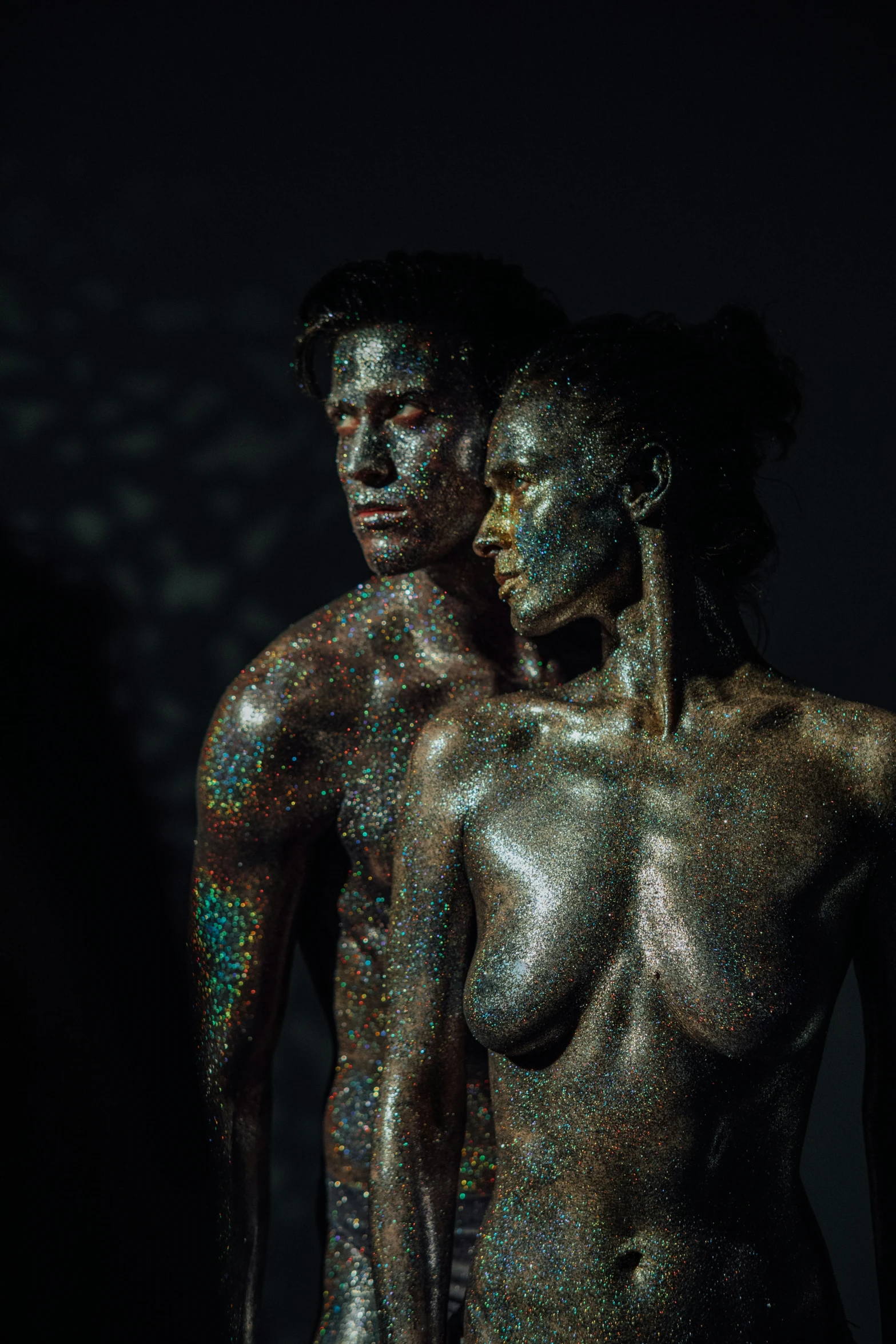 a man and a woman standing next to each other, by Adam Marczyński, unsplash contest winner, hyperrealism, golden bodypaint, black opals, iridescent skin, dirty skin