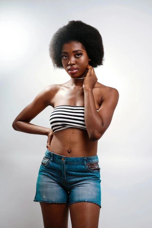 a woman in a striped top and denim shorts, by Lily Delissa Joseph, trending on pexels, long afro hair, tube-top dress, natural beauty expressive pose, 2 4 year old female model