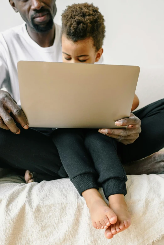 a man and a boy sitting on a bed with a laptop, by Carey Morris, pexels, papyrus, zoomed in, male and female, thumbnail