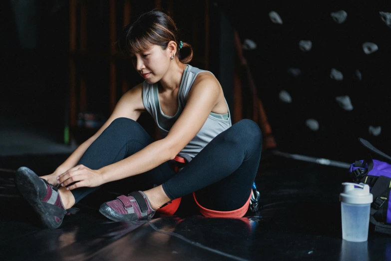 a woman sitting on the floor tying up her shoes, pexels contest winner, chun li at the gym, rock climber, avatar image, maintenance photo