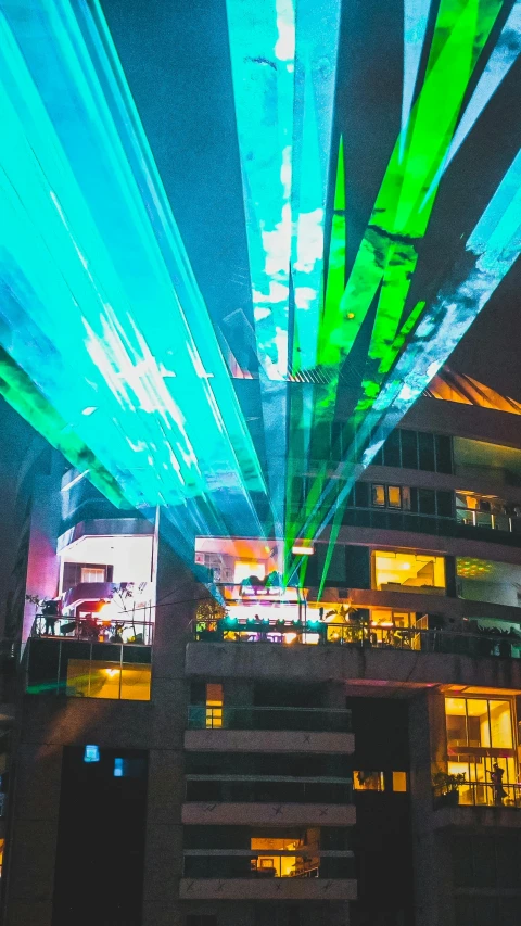 a very tall building with a lot of lights on it, a hologram, by Josh Bayer, unsplash contest winner, photograph of three ravers, laser beam ; outdoor, 3/4 view from below, panoramic shot