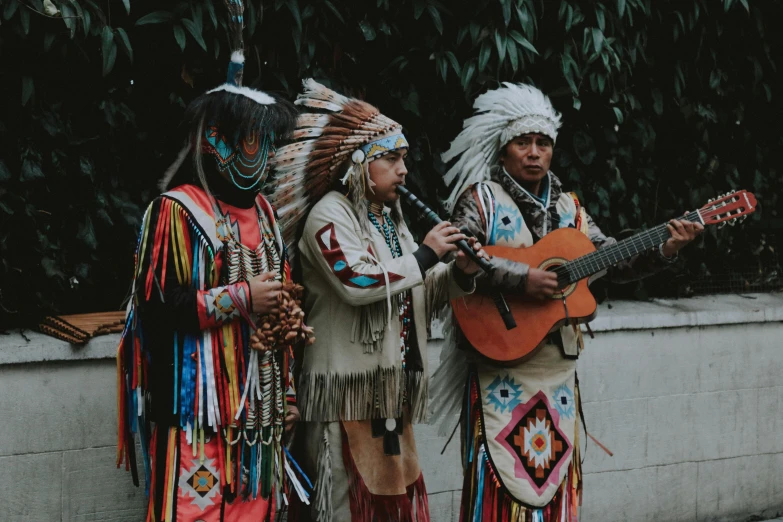 a group of people standing next to each other holding guitars, pexels contest winner, hurufiyya, feather native american headgear, traditional dress, thumbnail, beans