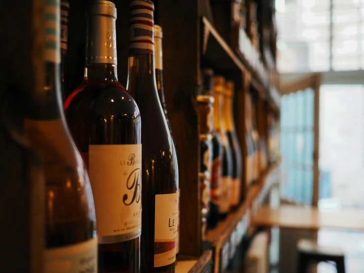 a row of wine bottles sitting on top of a wooden shelf, pexels contest winner, inside a bar, whites, local heroes, brown