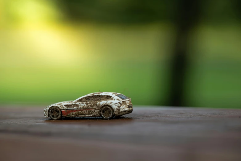 a toy car sitting on top of a wooden table, inspired by Filip Hodas, unsplash, photorealism, covered in dirt, sportscar, micro detailed, hyper composed